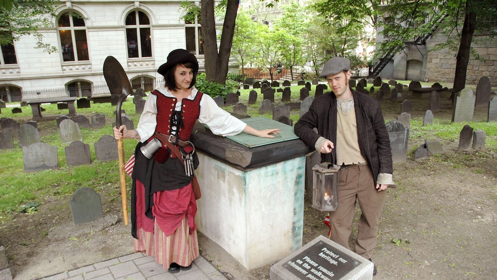 Ghosts and Gravestones Tour guides at a cemetery with a shovel in Boston