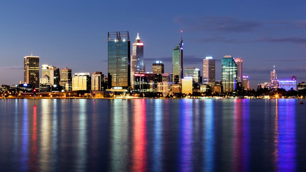 A view of the perth city skyline from a river at sunset