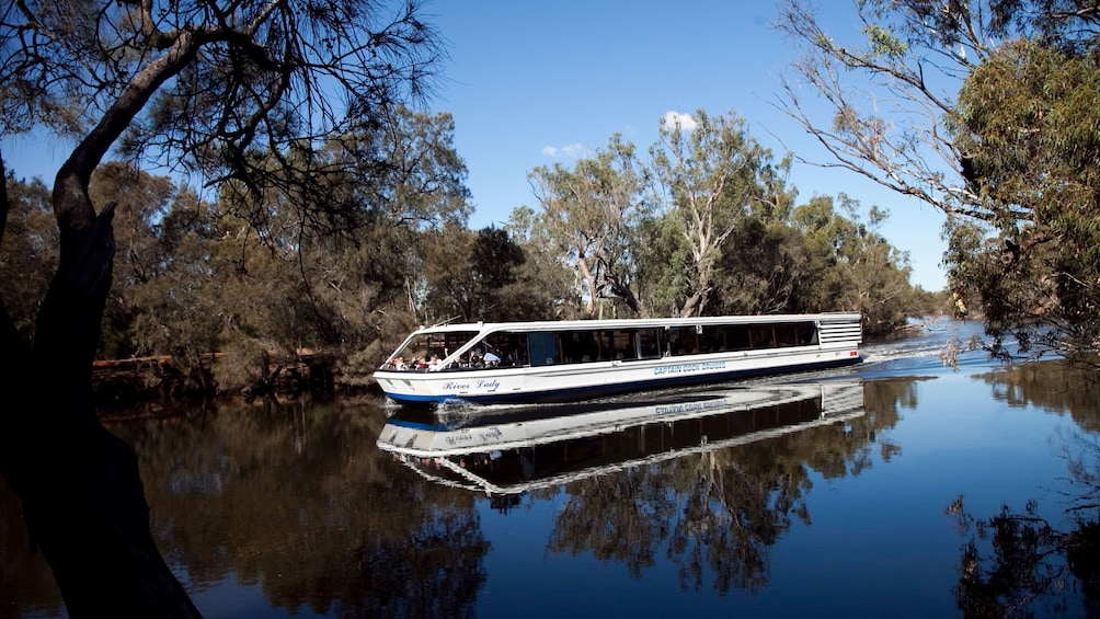 A cruise boat sailing up a river in perth