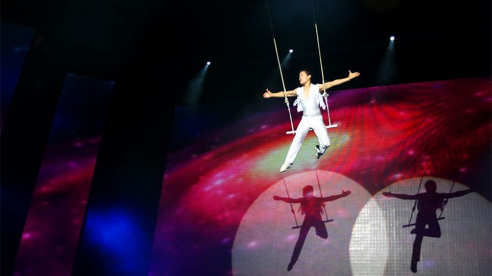 Male performer sitting on a swing while performing a Award-winning Shanghai Acrobatics Show in Shanghai 