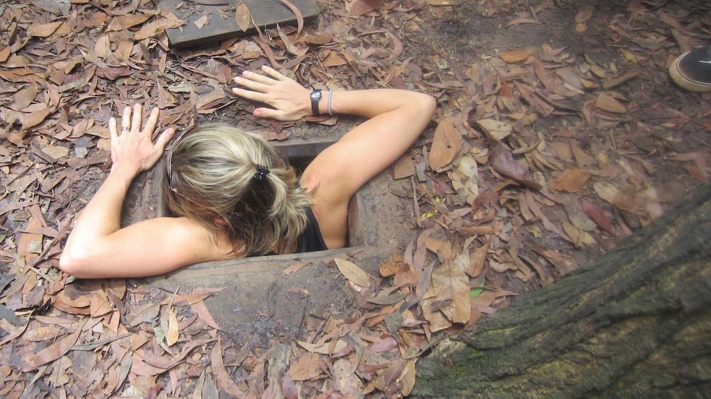 Woman climbing out of the Cu Chi Tunnels in Tay Ninh Vietnam 