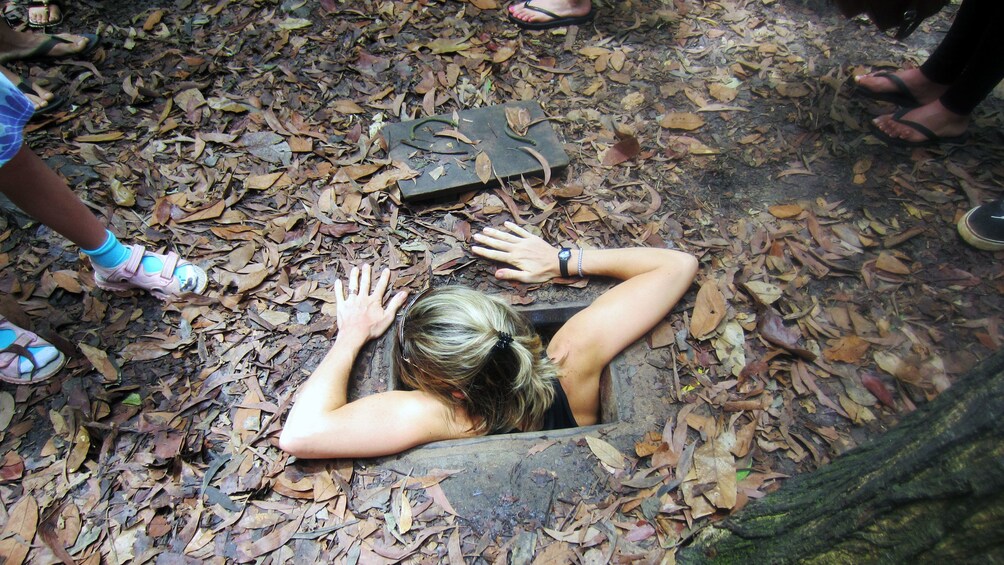 Woman climbing out of the Cu Chi Tunnels in Ho Chi Minh City 