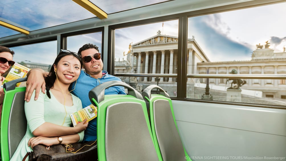 Couple listening to audio tour on Hop-On Hop-Off bus in Vienna