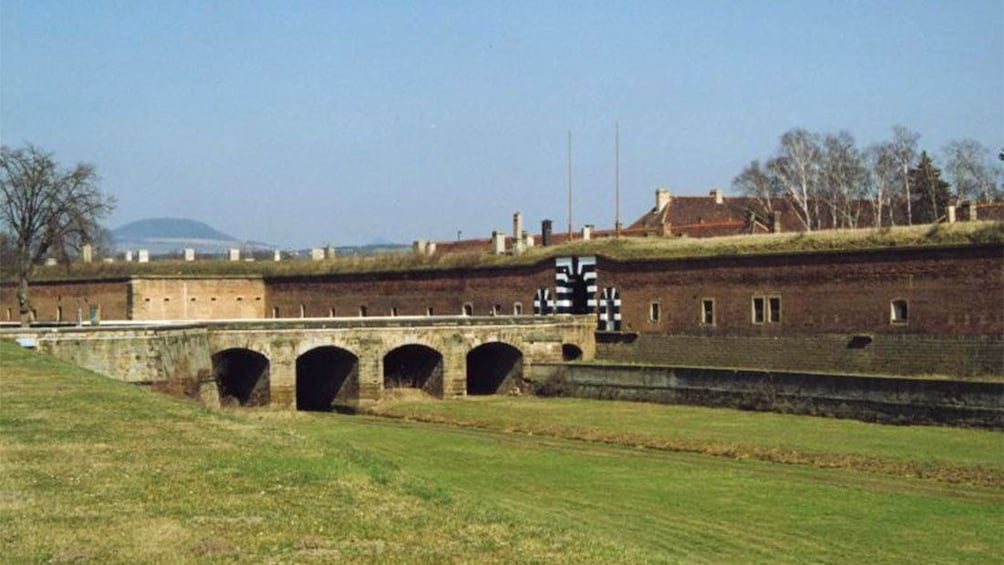 Bridge leading to black and white arched entrance to a fortress at the Terezin Concentration Camp in Prague