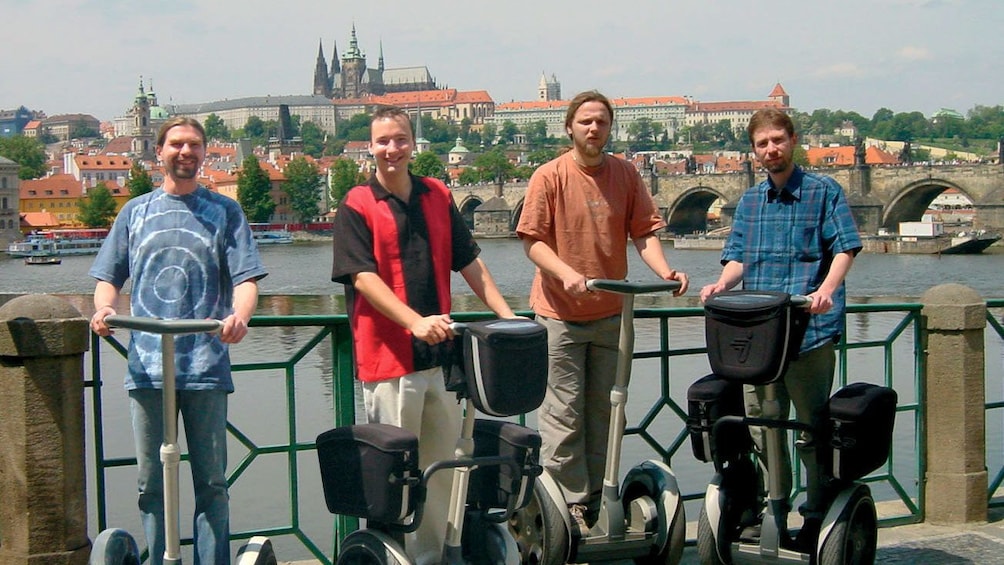 Segway group on a bridge with the Prague Castle in the background across the river in Prague