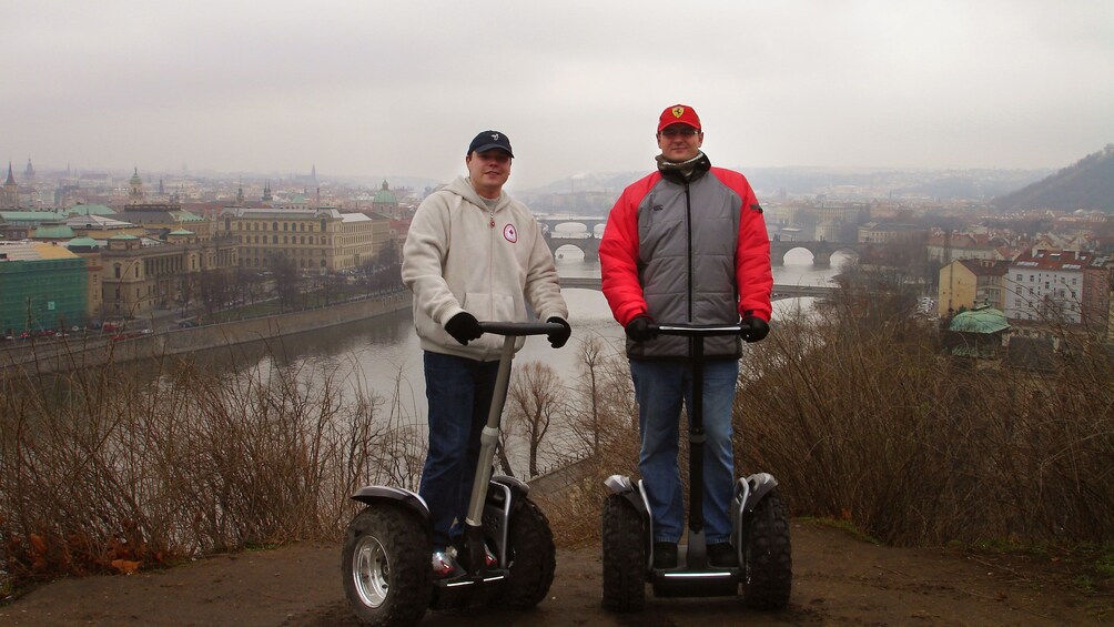 Segway riding pair at a lookout with the river and city in the background in Prague