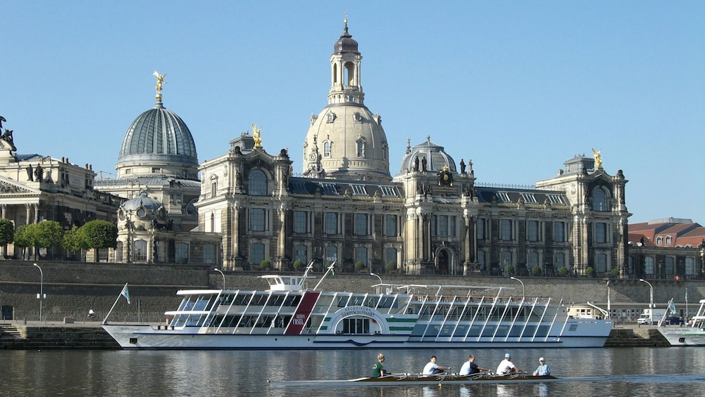 Boats line the bank the river near a cathedral in Dresden