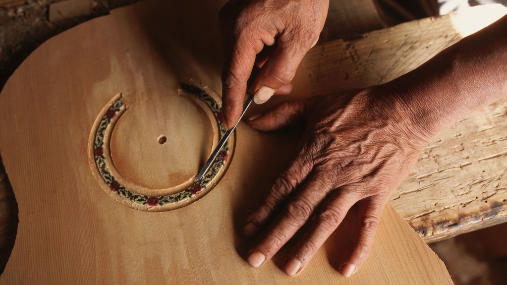 Man carving details into an acoustic guitar