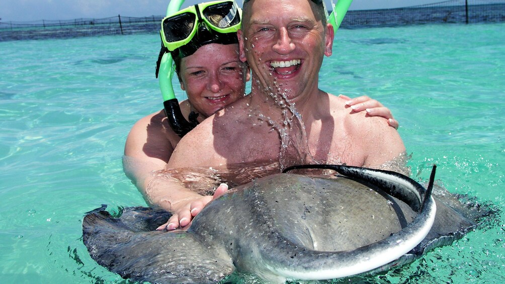 Show item 2 of 5. Couple holding stingray in water