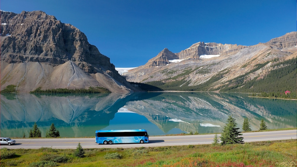 Tour bus driving past a crystal clear lake in Banff