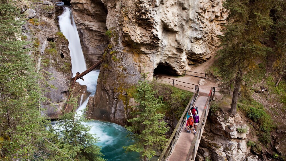 Group walking past a scenic waterfall in Banff