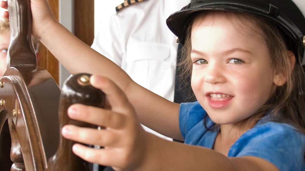 Young girl pretending to steer the Louis Jolliet river boat along the Saint Lawrence River