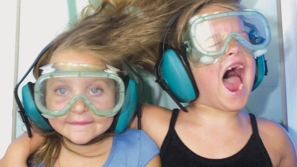 Two girls experiences a the affects of a wind tunnel