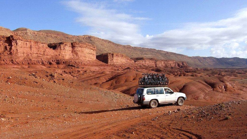 Jeep parked on a field among the red rocks of Marrakech