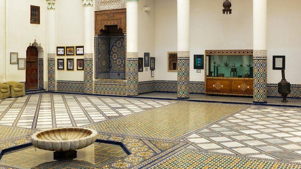 Artifacts on display among the colorful mosaic floor and pillars at the Museum of Moroccan Arts in Marrakesh