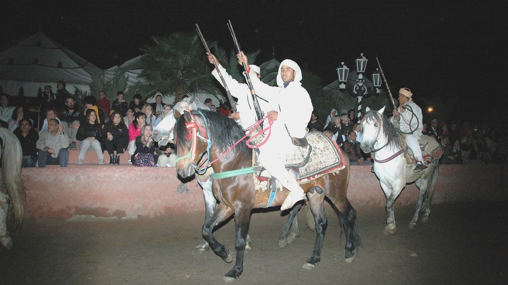 Riders with rifles on horseback during at night in Marrakech