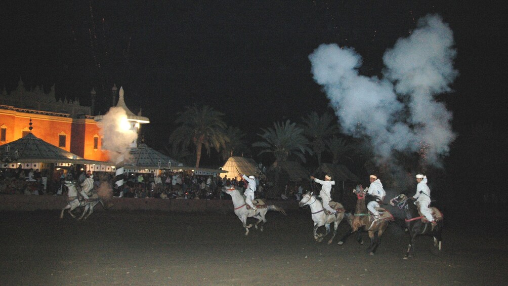 Horses and riders running during the Fantasia tribal horse charge at night in Marrakech