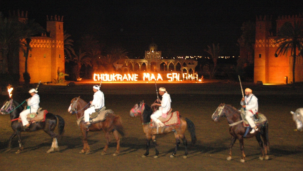 Row of horses and riders at night in Marrakech