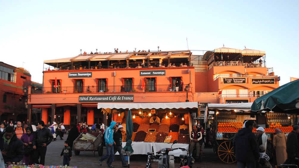 Fruit and vegetable stalls with restaurants behind at a market in Marrakech