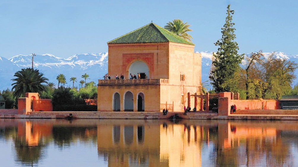Tour group on upper balcony of the pavilion at the Menara gardens with mountains in the background in Marrakech