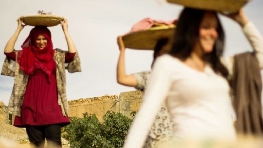 Tourists and locals carrying baskets on their heads in a village near Marrakech