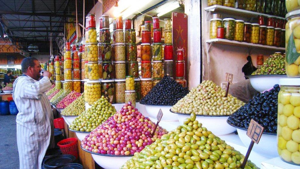Large bowls of fruit and jars of pickled goods for sale at a market stall in Marrakech