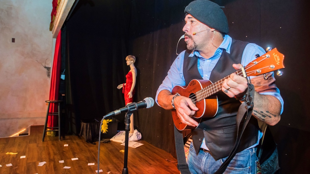 Man playing a Ukelele  with a mannequin 