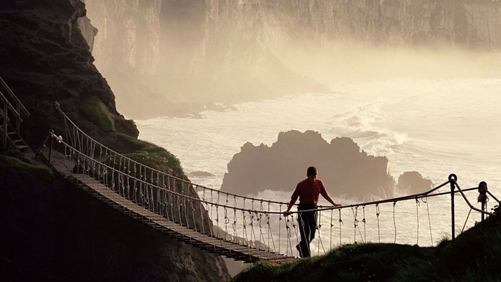 man walking bridge above chasm at Giants Causeway in Dublim