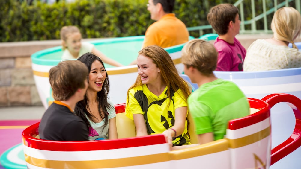 Show item 3 of 10. Four young adults in a teacup amusement ride at Disneyland