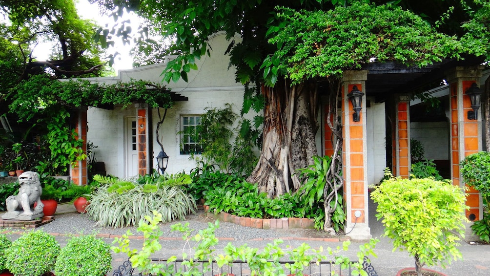 Colorful gardens outside an old house with tiled columns in Manila