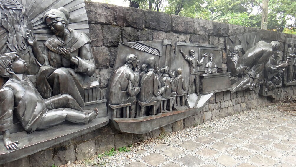 Metal sculptures along a stone wall in Manila