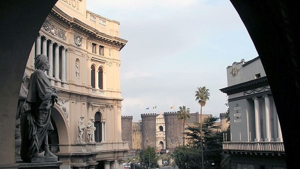 Charger l’élément 5 sur 5. View through an archway at historic buildings and Castel Nuovo in the distance in Naples