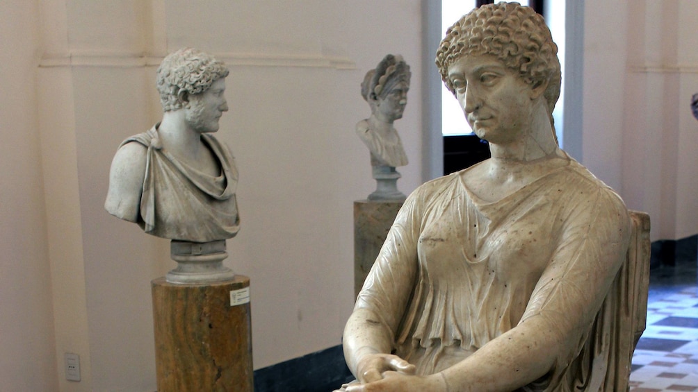 Busts and a statue of a woman in a classical style at the Archaeological museum in Naples