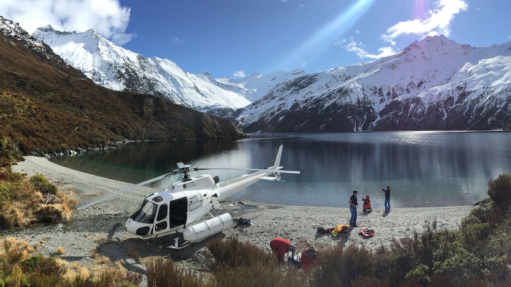 Helicopter next to a lake on a mountain top