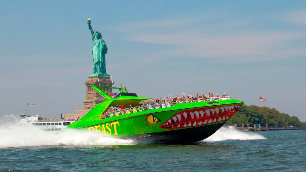 Beast speedboat with passengers zooming past the Statue of Liberty in New York
