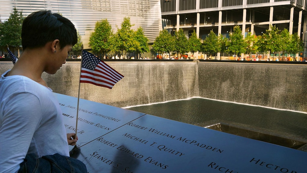 Person reading engraved names at 9/11 memorial in New York
