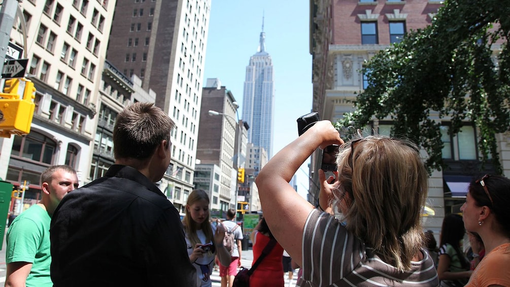 Group of people taking photos of the Empire State Building in the distance