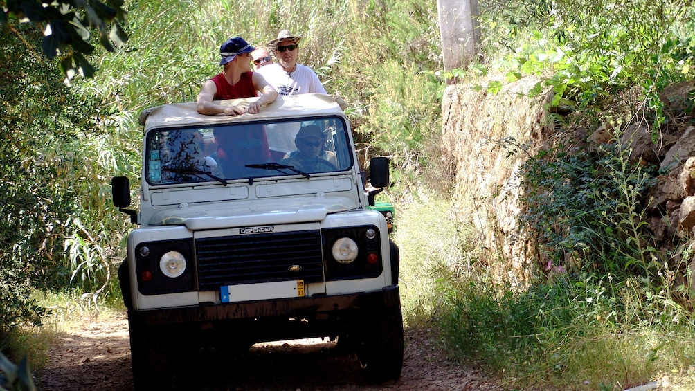 Jeep riding passengers stand and admire the lush green surroundings in the the Algarve