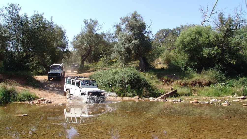 Row of jeeps splashing through water in the Algarve