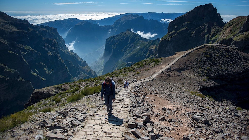 People walking up a path surrounded by scenic peaks in Madeira