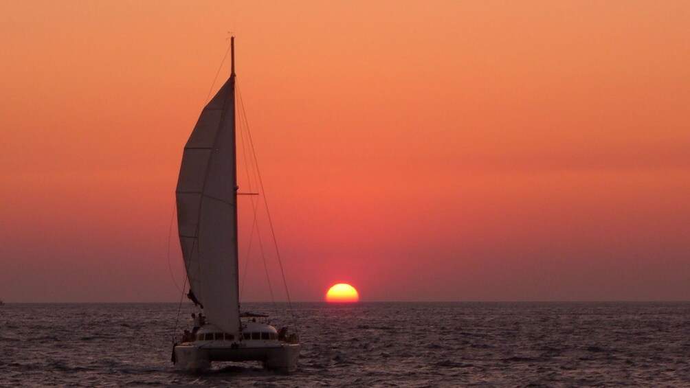 Sailboat on the waters as the sun goes down in Santorini