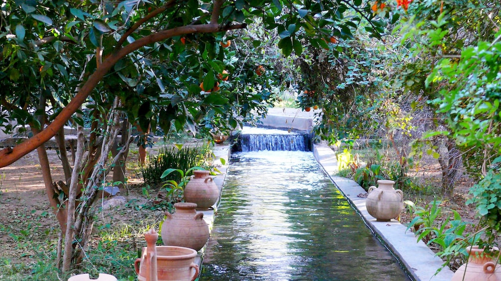 Clay pots sit along a stream running through a garden in Taroudant