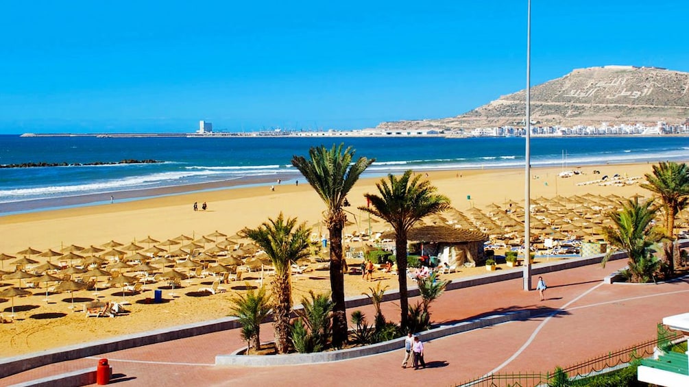 People walking on the promenade along the sandy coast of Agadir