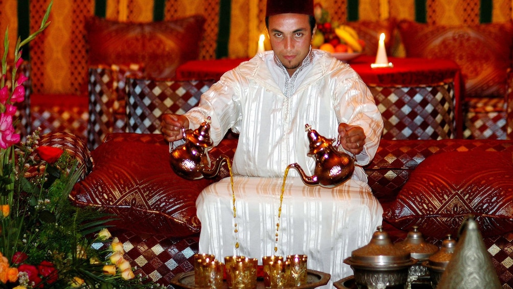 Server pouring two tea pots simultaneously in Agadir