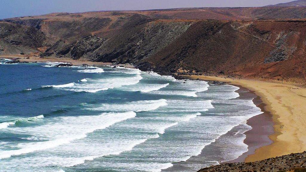 Waves rolling onto a sandy beach in Assaka