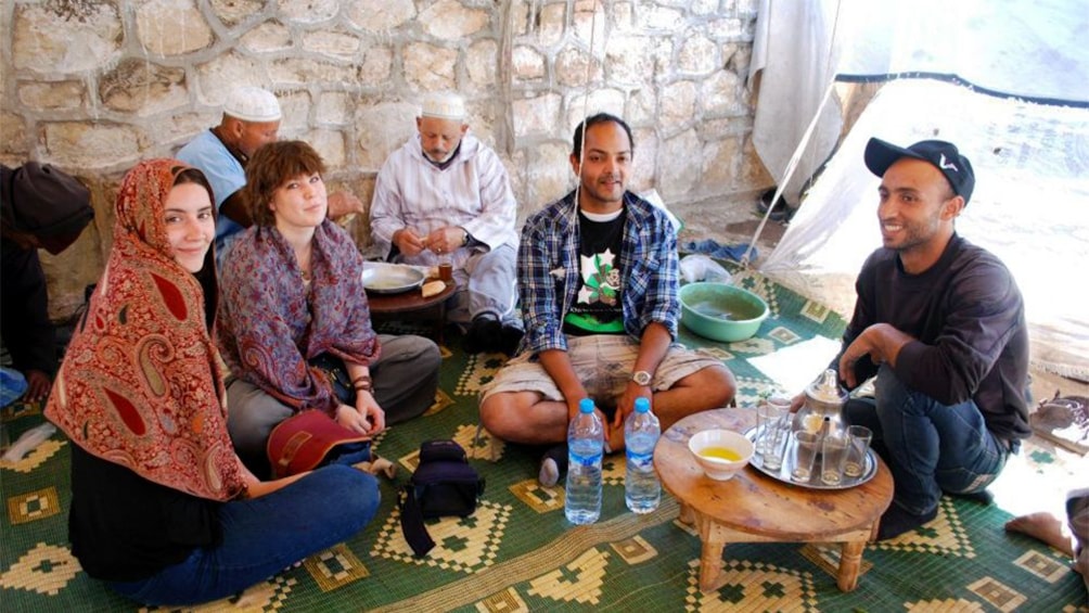 Tour group sitting on a rug and enjoying refreshments in Agadir
