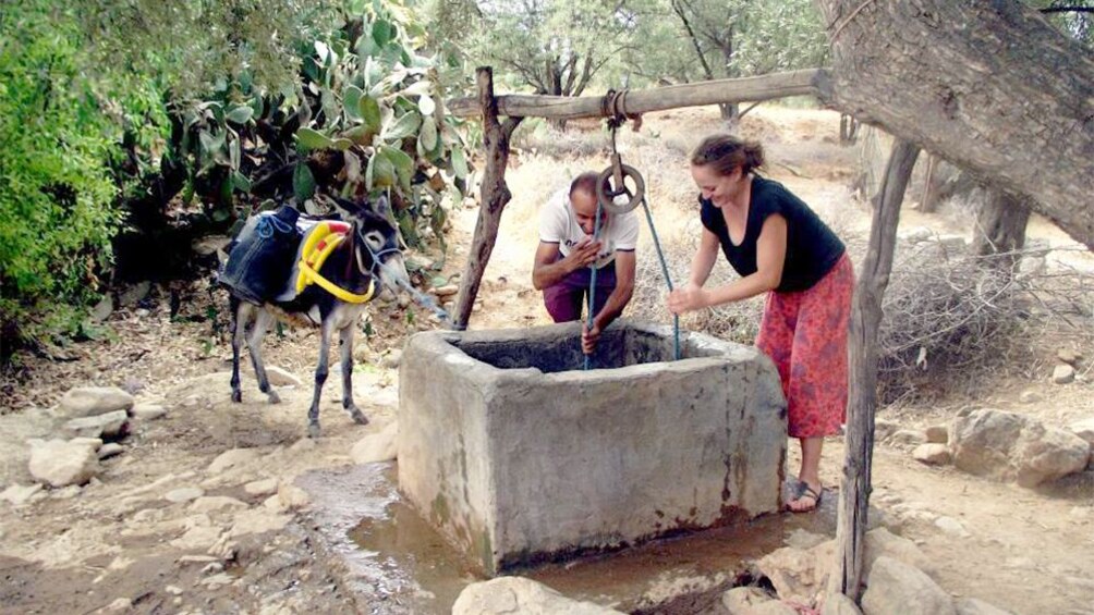 People collecting water from a well with a donkey parked nearby in Agadir