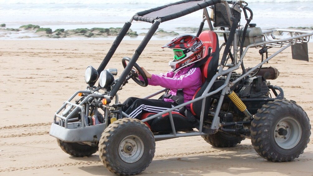 Young girl driving a dune buggy on the beach in Agadir