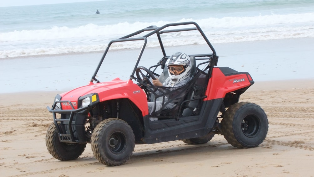 Kid driving a dune buggy on the beach near the water in Agadir