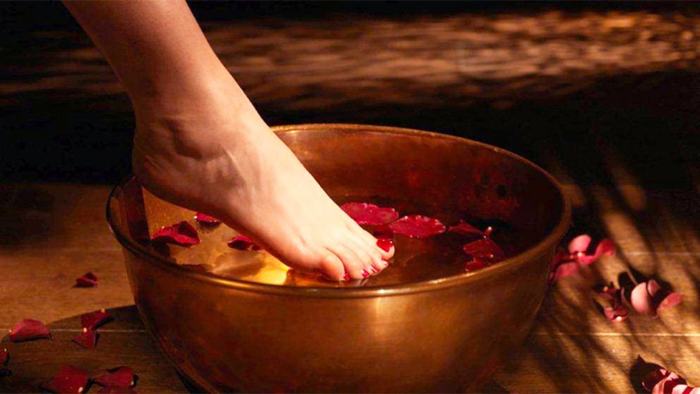 Woman placing foot in a rose petal foot bath at a spa in Morocco